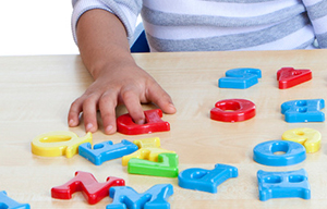 child's hand on plastic letter