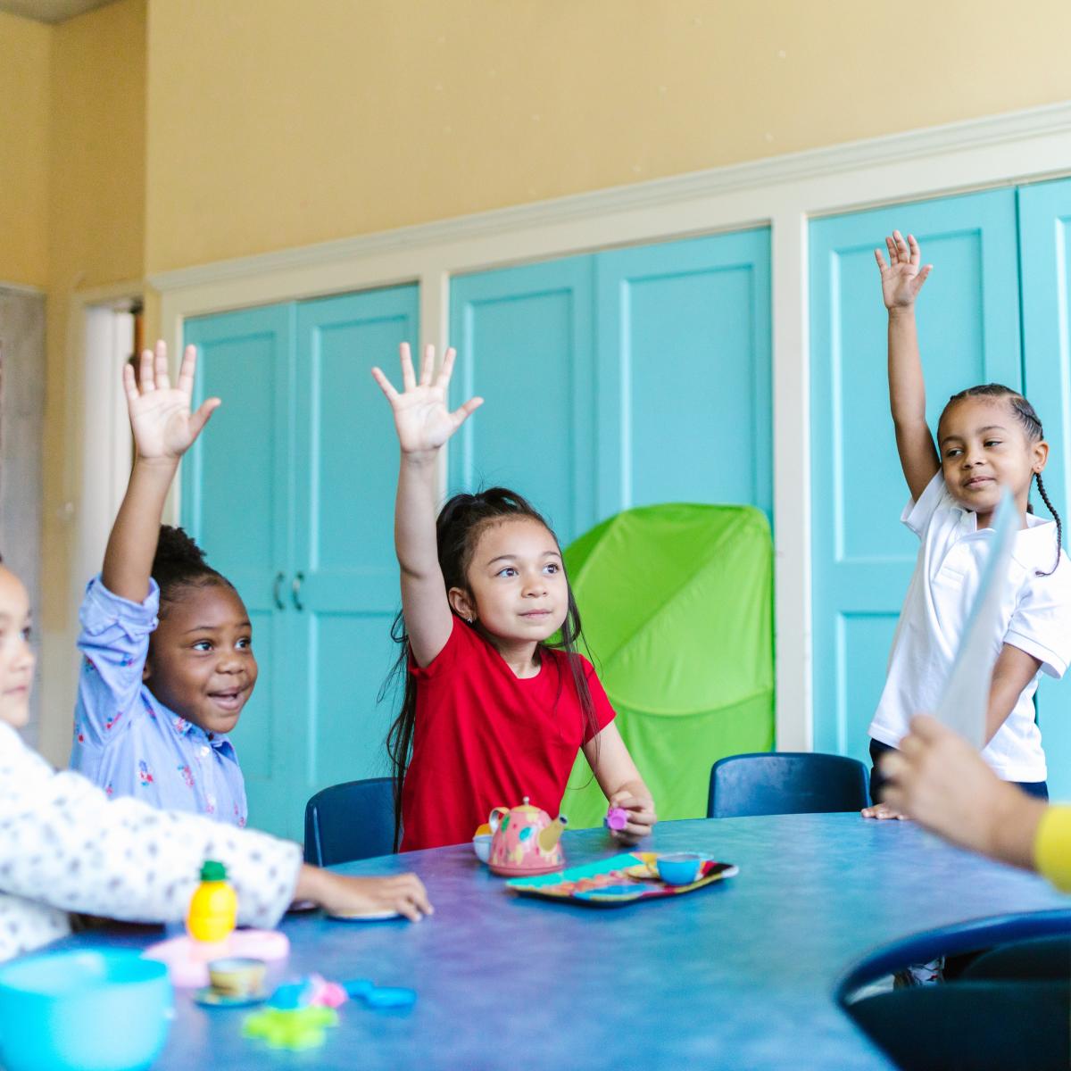 Kids raising hands in classroom